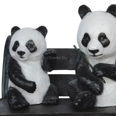 Три бронзовых статуи медведей панды, сидящие на садовой скульптуре скамейки